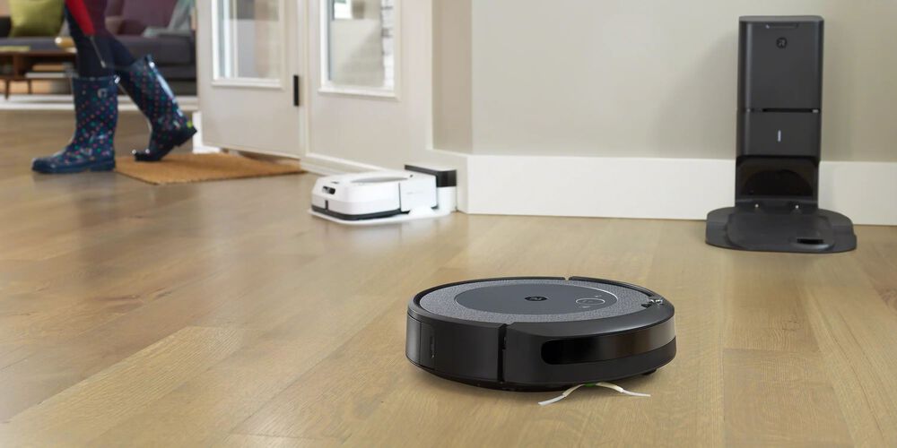Un robot Roomba negro con otro modelo en blanco en el fondo